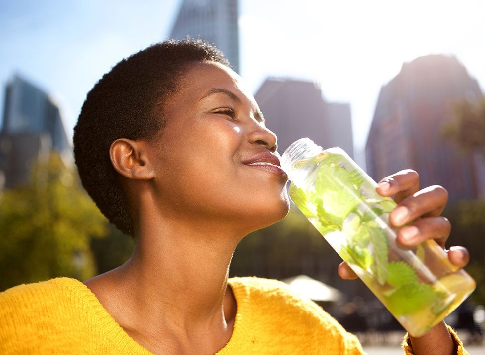 Uma mulher bebe água com limão e hortelã