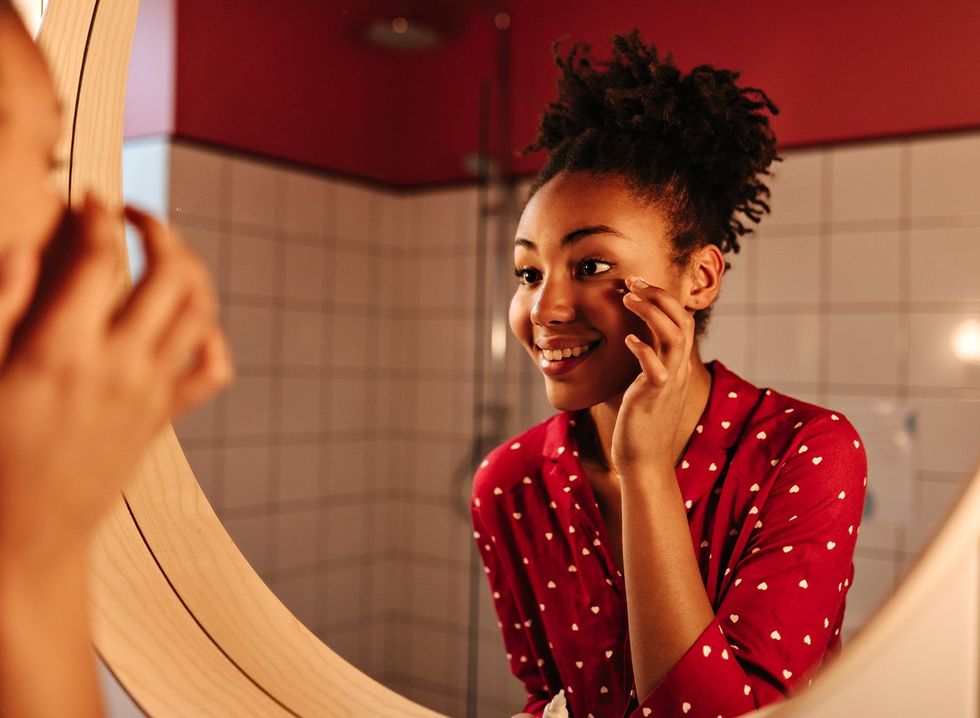 Mulher feliz com pele bonita olhando no espelho