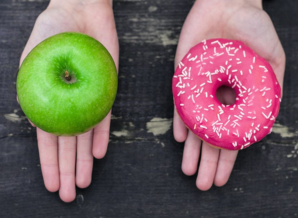 Uma maçã em uma mão e um doce na outra