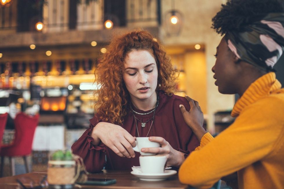 Uma jovem está conversando com uma amiga em um café