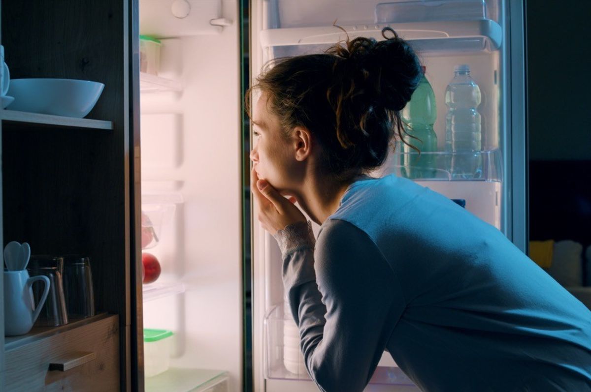 Uma mulher olha na geladeira tarde da noite em busca de um lanche