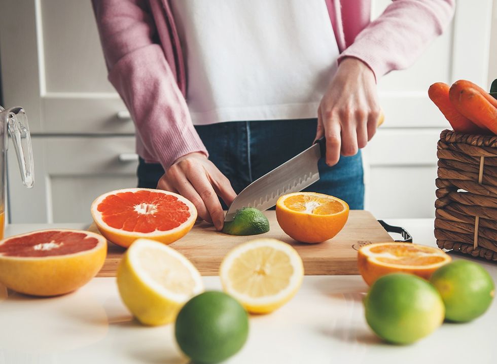 Uma mulher está cortando frutas e legumes em sua cozinha